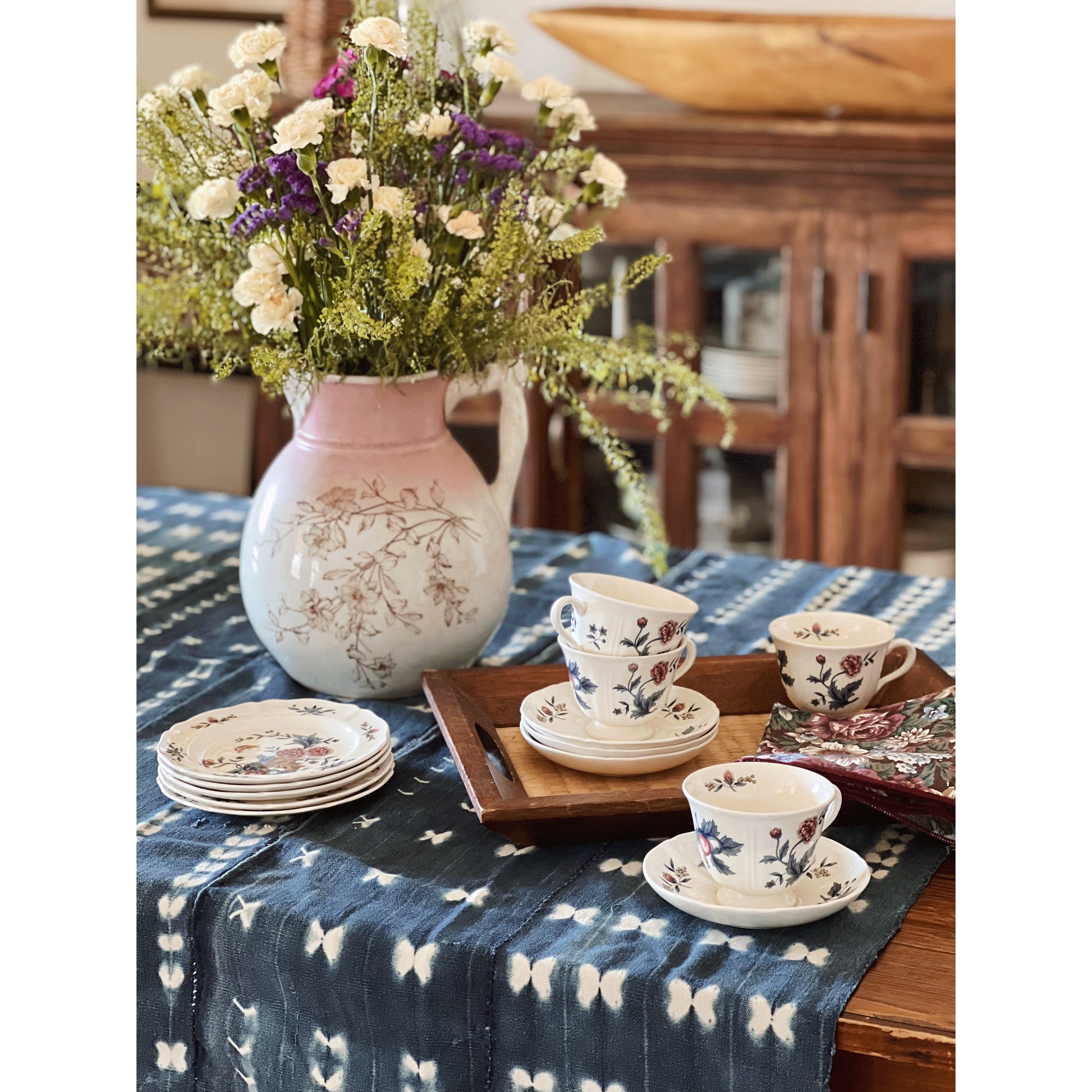 navy floral teacups and saucers on a table with fresh flowers and indigo linens