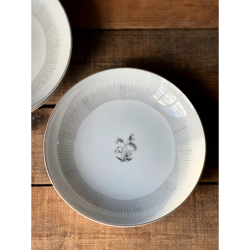 White ceramic bowl with a mid century floral design on a wooden surface