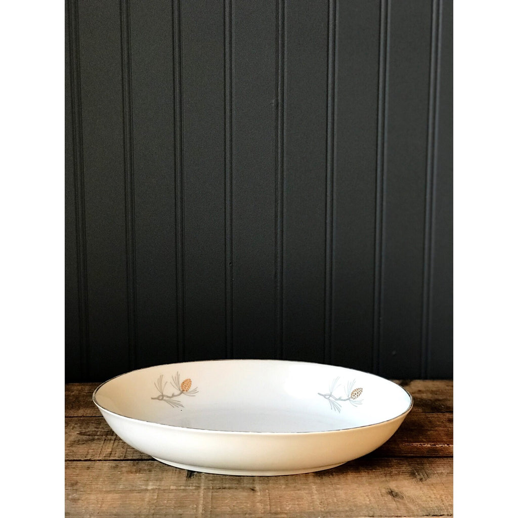 Sone China Japan Pinecone Oval Vegetable Serving Bowl on a wooden surface against a black paneled wall.