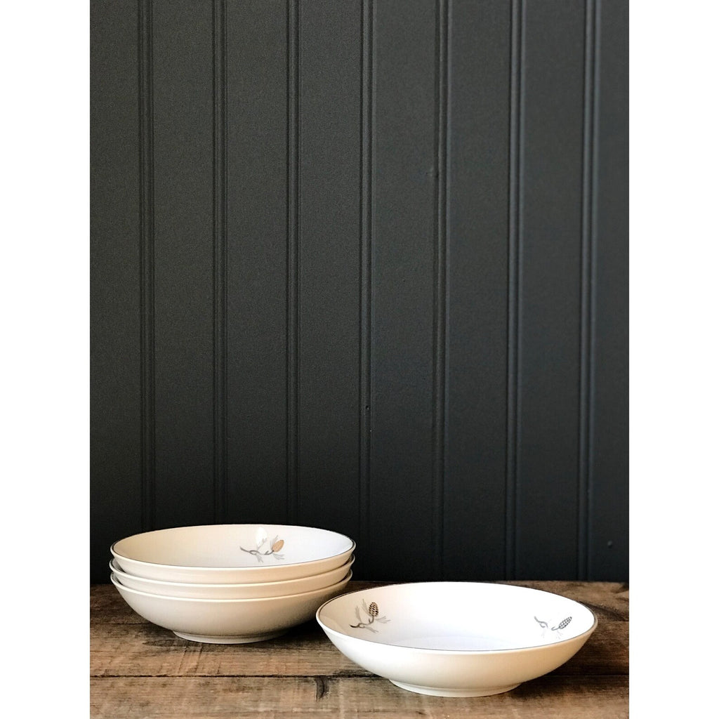 Set of white porcelain bowls with floral patterns on a wooden surface against a black paneled wall.